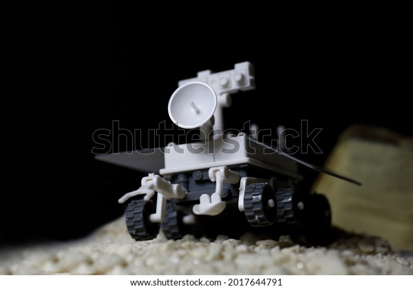 lunar rover walking on lunar surface with\
crater on background