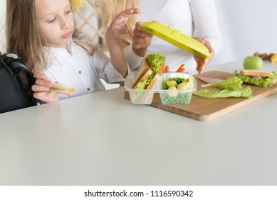 Lunch Box With Appetizing Food And School Bag On Kitchen Background. Homemade School Sandwiches.Packing In School Lunchbox.Mom Preparing School Snack Or Lunch For Her Daughter In Home Kitchen.