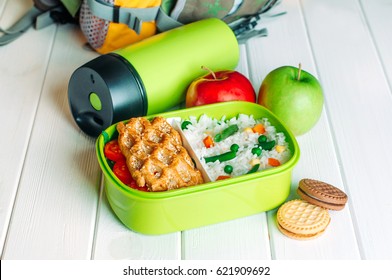 Lunch Box Filled With Rice And Sandwich Near Thermos, Fresh Apples And Biscuits In Front Of Kids School Backpack On White Wooden Background ; Selective Focus