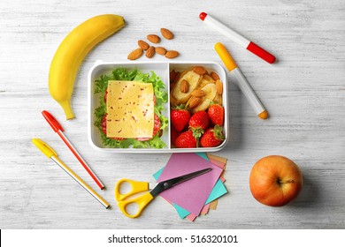 Lunch Box With Food And Stationery On Wooden Background, Top View