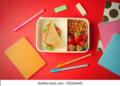 Lunch Box With Food And Stationery On Red Background, Top View