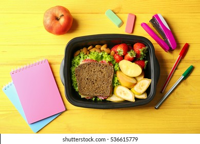 Lunch Box With Food And Stationery On Wooden Background, Top View