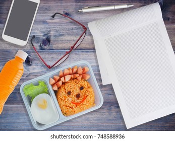 Lunch Box For Kids With Mobile Phone And Note Pad On Wooden Background. Back To School Concept.