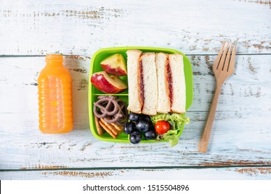 Lunch box set of Peanut butter with strawberry jam sandwich with cracker, apple in box and orange juice. Kid bento pack for school. Top view. - Powered by Shutterstock