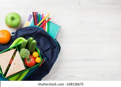 Lunch Box With Vegetables And Sandwich On Wooden Table. Kids Take Away Food Box And School Backpack. Top View With Copy Space