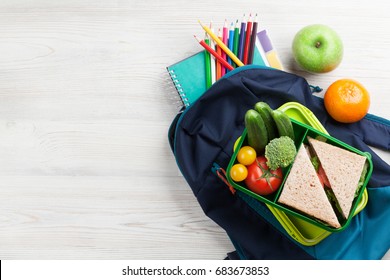 Lunch Box With Vegetables And Sandwich On Wooden Table. Kids Take Away Food Box And School Backpack. Top View With Copy Space