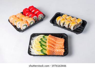 Lunch Boxes With Sushi Set. Assorted Fresh Rolls Philadelphia, California, Sashimi On Light Background. Tasty Vegetarian Lunch.Food Delivery, Takeaway Concept. Japanese Cuisine Seafood. 