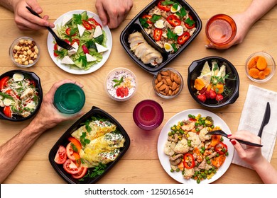 Lunch Breack In Modern Office. Four People Eating Healthy Meals From Take Away Lunch Boxes And Plates At Wooden Table. Concept, Top View