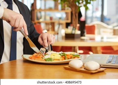 Lunch break. Cropped closeup of a businessman cutting food on his plate during business lunch in the restaurant