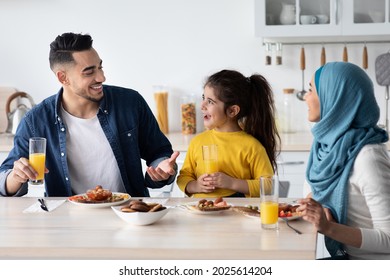 Lunch At Home. Happy Muslim Family Of Three Having Meal Together, Cheerful Middle Eastern Parents And Little Daughter Eating Tasty Food While Sitting At Table In Kitchen, Closeup Portrait