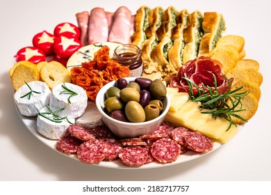 Lunch meal or appetiser including a single dish with salami, pepperoni, brie cheese, ham. One plate with dinner or appetizer consisting of salumi (cured meat), cheeses, nuts and focaccia bread - Shutterstock ID 2182717757
