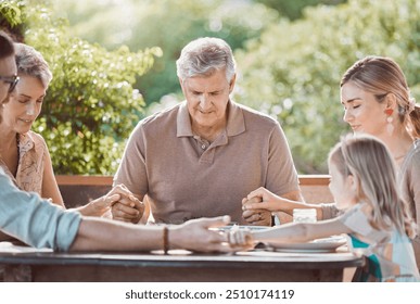 Lunch, outdoor and family in prayer at table together with gratitude, faith and weekend gathering home on patio. Men, women and child in backyard giving thanks for food in worship, bonding and peace - Powered by Shutterstock