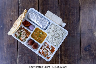 Lunch pack in Indian restaurants with roti subji dal rice sweet and pickle papad and butter milk North Indian Lunch Pack top view selective focus wooden background vegetarian packed food