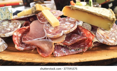 Lunch Platter Of Fresh Gourmet Cheese, Sliced Cured Meats, Ham, Fatty Sausages, Served On Wooden Plank In Apres Ski Restaurant .