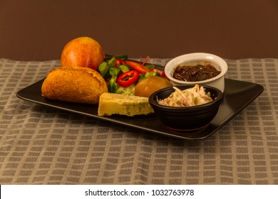 Ploughmanâ??s Lunch With Stilton Cheese, Pickle, Pickled Onion, Salad, Coleslaw And Bread Roll And Apple.