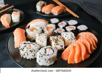 Lunch at the sushi bar. Set of sushi and rolls unagi maki on a black plate on dark background top view. Sushi Delivery to Home Order Online. Takeout coronavirus food. 