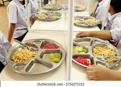 Lunch For Thai Elementary School Students And Shield Partition On The Table For Social Distancing In The New Normal Life.