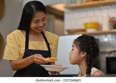 Lunch Time With Asian Family, A Mother Feeds Pizza To Her Daughter, Children Are Eating And Tasting Italian Homemade Pizza. 