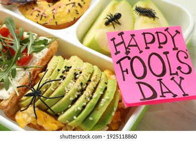 Lunchbox With Fake Spider, Bugs And Happy Fools' Day Note On Table, Closeup