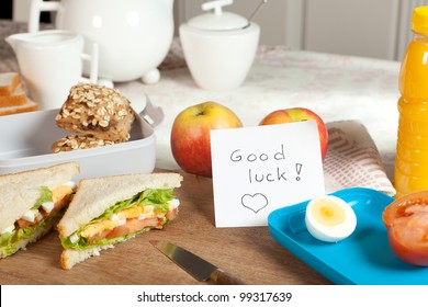 Lunchbox On Breakfast Table With Good Luck Note