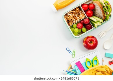 Lunchbox with a sandwich, fruits, nuts, and essential school supplies on white background. - Powered by Shutterstock