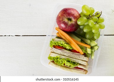 Lunchbox With Sandwich, Vegetables, Fruit On White Background. Top View