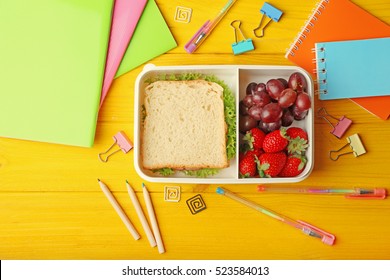 Lunchbox With Tasty Meal And Stationery On Yellow Wooden Background