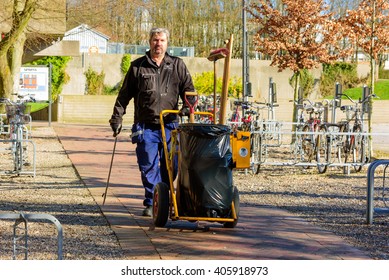 Lund, Sweden - April 11, 2016: Working Man Walking Toward You With Garbage Cart And Tool For Picking Up Trash From The Street. An Everyday Hero Keeping Our World Clean.