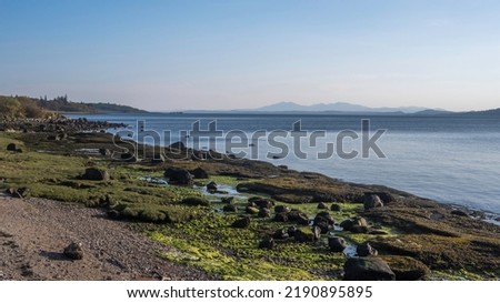 Lunderston Bay, Firth of Clyde, Scotland. Looking south past Wemyss Bay pier to the distant hills of the Isle of Arran.