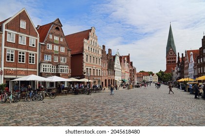 Luneburg, Germany - July 4, 2019: Historical buildings and St. Johannis church tower and people walking on the Am Sande town square in the old center of Luneburg, Germany on July 4, 2019