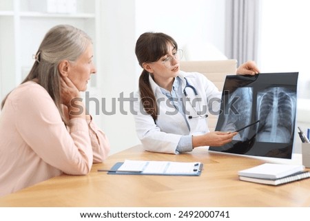 Lung disease. Doctor showing chest x-ray to her patient at table in clinic