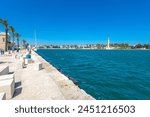 Lungomare in Brindisi, a pedestrian walkway next to the beach and surrounding old town. Row of palms are visible on a warm spring day