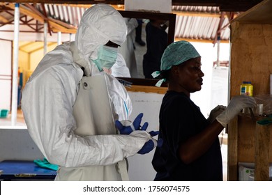 Lunsar, Sierra Leone - April 29,2015: A Nurse And A Medical Worker Prepared With Safety Equipment To Enter Dangerous Zone Of An Ebola Treatment Center To Check Patients Evolution. Pandemic Context