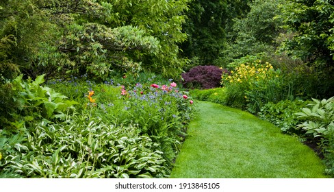Lush green botanical garden - blooming spring flowers and lawn path. - Shutterstock ID 1913845105