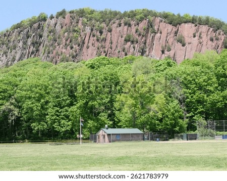 Lush green forest meets dramatic rocky cliffs at West Rock Ridge in New Haven, CT. A striking spring scene filled with vibrant foliage