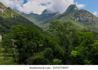 Lush, green forests blanket the lower slopes, while towering, jagged peaks of Garda Hills in Ledro Valley at Garda Lake, Trentino, Northern Italy. Hiking trail Sentiero del Ponale in Italian Alps - Powered by Shutterstock