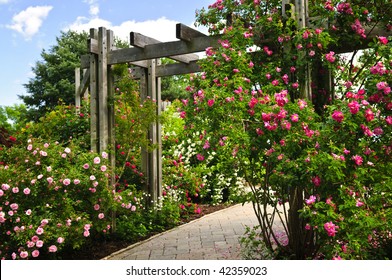 Lush Green Garden With Stone Landscaping, Flowers, And Arbor