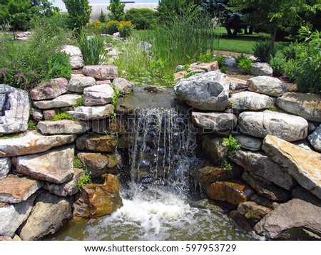 A lush green garden with waterfall cascading down the rocky stones