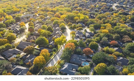 Lush greenery master planned community subdivision colorful fall leaves and row of single-family homes with swimming pool in upscale neighborhood Dallas, North Texas, USA. Aerial view subdivision