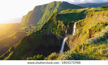 Lush paradise views over green valley, dramatic cliffs and cascading waterfall at Flores Island, The Azores, Portugal