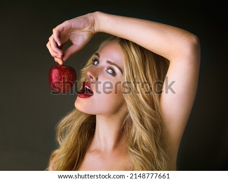Lust at first bite. Studio shot of a gorgeous young woman eating a red apple suggestively against a dark background.