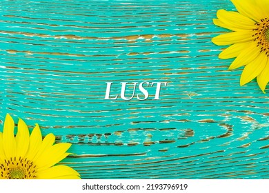 LUST - text, yellow flowers, sunflowers, wooden background (copy space).