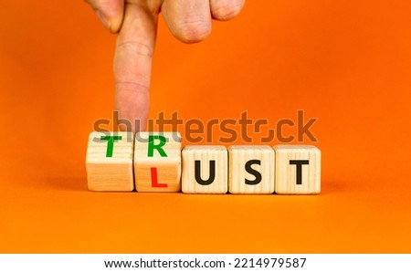 Lust or trust symbol. Businessman turns wooden cubes and changes the words 'lust' to 'trust'. Beautiful orange table, orange background. Business and lust or trust concept, copy space.