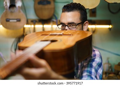 Lute Maker Shop And Classic Music Instruments: Young Adult Artisan Fixing Old Classic Guitar. The Man Looks Carefully At Bridge And Arm To Check The Wood Curvature