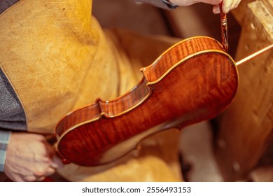 Luthier carefully varnishing a handcrafted violin in his workshop, showcasing italian craftsmanship and woodworking skills - Powered by Shutterstock