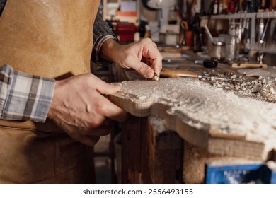 Luthier meticulously shaping wood with gouge, creating intricate details on a violin's surface in his workshop