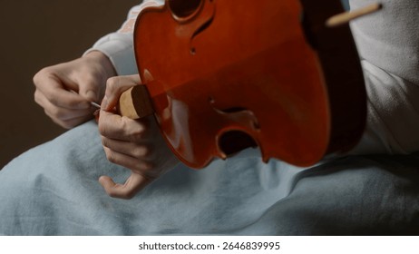 Luthier working diligently in a workshop, carefully assembling violin parts with specialized tools and techniques, showcasing craftsmanship and dedication to the art of instrument making