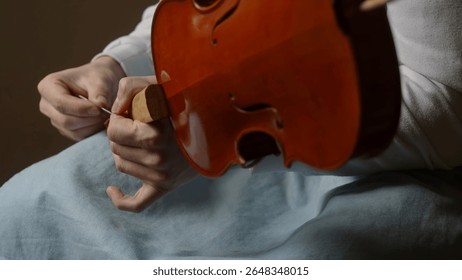 Luthier working diligently in a workshop, carefully assembling violin parts with specialized tools and techniques, showcasing craftsmanship and dedication to the art of instrument making - Powered by Shutterstock - Get 15% off with code: PIKWIZARD15