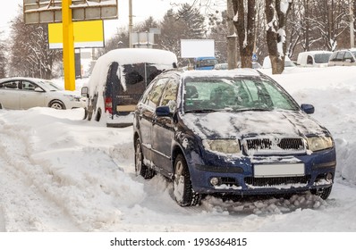 Lutsk, Ukraine - February 12,2020: Stuck car in snow and ice. City street after blizzard. Buried vehicle in snowdrift. Parking in winter after snowfall. Uncleaned road. Record-breaking amounts of snow