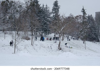 Lutsk, Ukraine - January 14 2020. Winter Fun. People Are Sledding From Slide In City Park. Parents And Children Enjoy Winter. Fun On The Snow In The City.